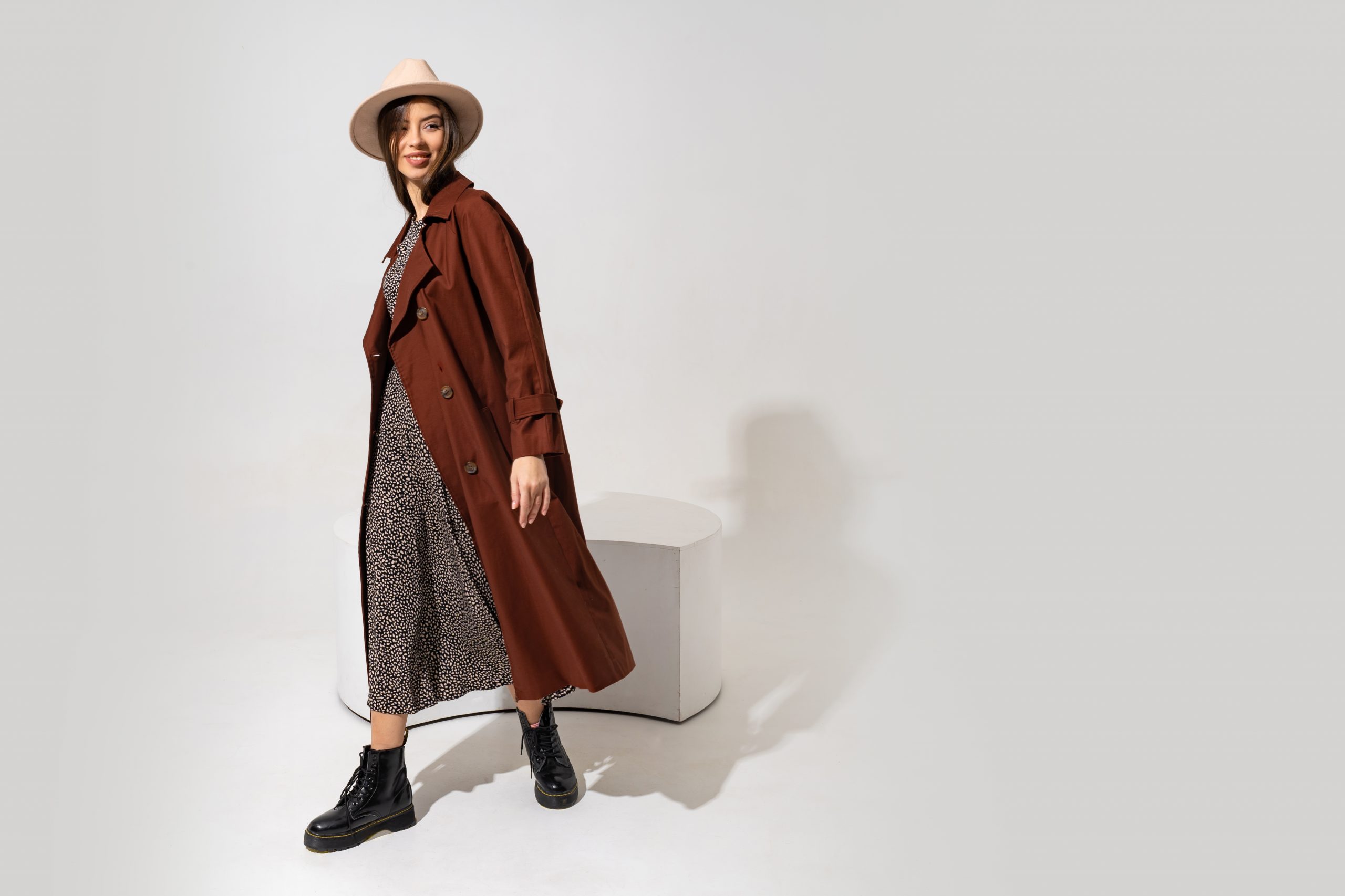 Winer fashion look. Stylish brunette model in brown coat  and beige hat posing in studio on white background. Full lenght. Copyspace fo text.